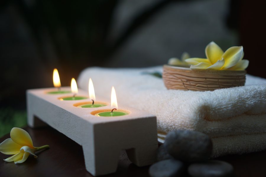 Spa-style setting with candles, folded towels, and flowers evoking a luxury hotel scent
